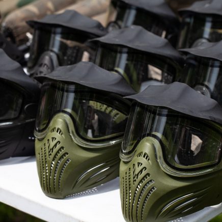 Closeup Photo of Paintball Gear Before Training At The Shooting Range. Protective Camouflage Mask at Table. Special protective mask for playing paintball